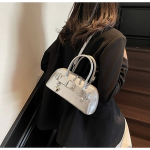 Détail du sac bowling argenté mat avec pendentif coeur et sangles à boucles sur modèle