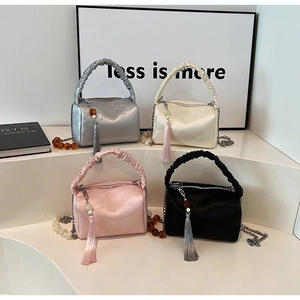 Detailed view of women's pleated pillow bags in silver, cream, pink, and black colors