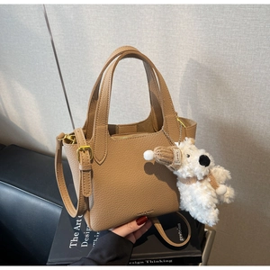 Detail of lychee pattern leather handbag with cute plush dog pendant and gold zipper