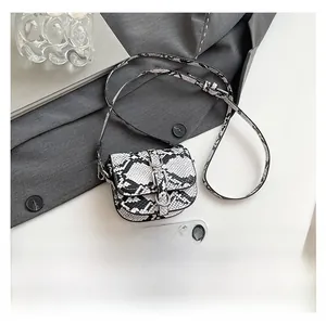 Mini snakeskin saddle bag shown next to a smartphone for size scale and comparison