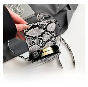 Detailed internal capacity showing snakeskin mini saddle bag with lipstick and compact