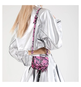 Rear view of a model wearing a pink and black snakeskin mini saddle bag with silver buckle