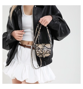 Close-up of mini snakeskin saddle bag with double ring buckle and slim shoulder strap