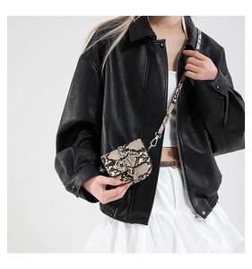 Close-up of snake skin pattern mini crossbody bag with silver hardware on black leather jacket