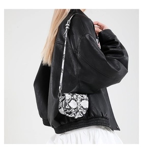 Close-up of a mini saddle bag with black and white snakeskin texture on model