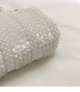 Detailed close-up of intricate white pearl beadwork and clear sequins on a mini handbag