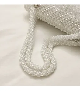 Detail of a white pearl woven handbag featuring a smooth adjustable shoulder strap