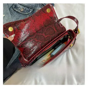 Detail view of the red and black snakeskin purse showing the inner lining and zipper pocket