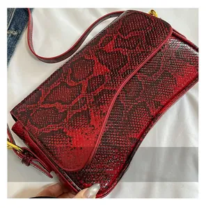 Close-up of red and black snakeskin texture with gold hardware and red trim detail