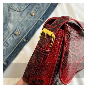 Detail showing the red snakeskin texture and golden buckle on this stylish handbag