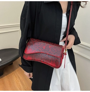 Detail of red and black snake skin crossbody bag with unique wavy base and bronze hardware
