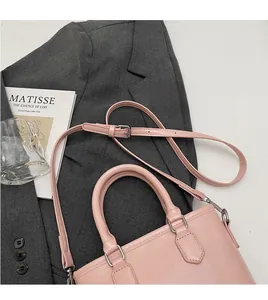 Sac seau en cuir ciré rose avec détails argentés et bandoulière sur un costume gris