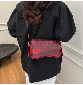 Close-up of red and black snakeskin texture on retro shoulder bag with golden rings