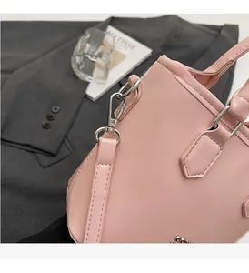 Détail de la quincaillerie en métal argenté sur un sac seau rose pâle en cuir huilé