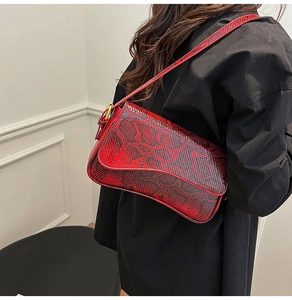 Detail of red snake pattern shoulder bag with adjustable strap worn by a model