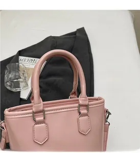 Détail du sac seau rose en cuir ciré avec poignées rondes et finitions métalliques