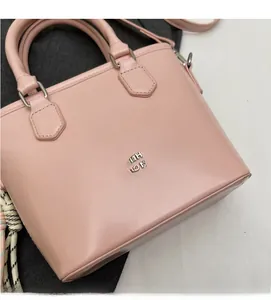 Détail du sac seau en cuir ciré rose avec logo métallique argenté et doubles poignées