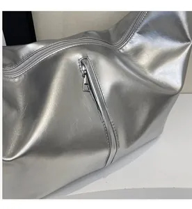 Détail du sac argenté métallisé avec fermeture éclair fluide et texture cuir grainé