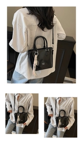 Détail du petit sac seau noir en cuir ciré avec lettrage blanc et breloque en corde