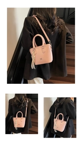 Sac seau en cuir rose pâle avec poignées, breloque à gland rayé et bandoulière fine
