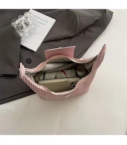 Spacious interior of pink pleated handbag showing phone, umbrella, and cosmetics