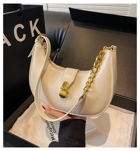Detail of off-white crescent underarm bag with gold chain and elegant metal lock closure