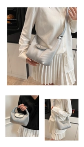 Detailed close-up of pleated silver tote bag with metallic texture and round buckle