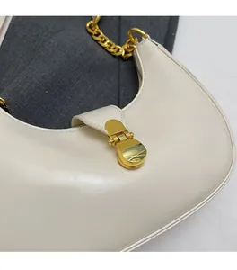 Detail of off-white crescent bag featuring soft leather texture and golden metal buckle