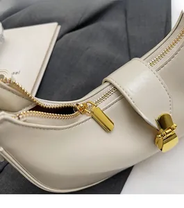 Detailed macro view of the gold zipper and textured synthetic leather on beige handbag