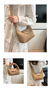 Close-up of beige pleated shoulder bag featuring fine accordion folds and leather strap