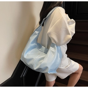 Détail du sac hobo bleu clair brillant avec large bandoulière porté par un mannequin