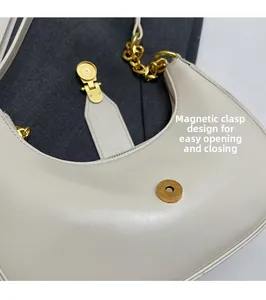 Detail of the magnetic buckle closure on a beige leather crescent-shaped shoulder bag
