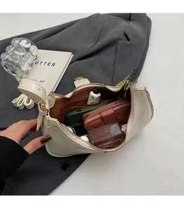 Top-down view of a cream shoulder bag showing spacious interior with zipper pocket and essentials