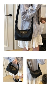 Close-up of black pleated PU shoulder bag with silver metal buckle and wide strap