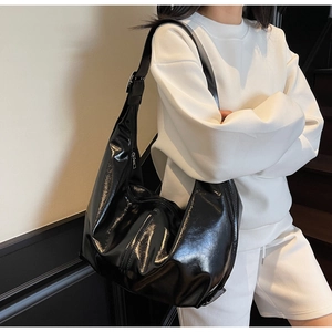 Détail du sac à bandoulière en cuir verni noir brillant avec un design spacieux et élégant
