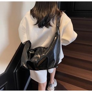Modèle portant un grand sac à bandoulière noir brillant dans l'escalier pour le travail