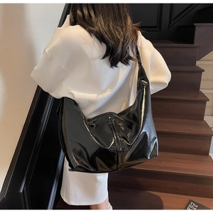 Détail d'un grand sac hobo noir brillant avec finition miroir et design minimaliste souple
