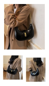 Detail of black glossy crescent bag with gold chain strap and vintage metal lock