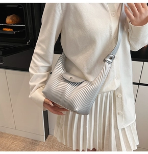 Detail of silver pleated crossbody bag with metallic finish and magnetic snap closure