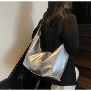 Détail d'un grand sac hobo argenté métallisé porté à l'épaule, vue de dos sur mannequin