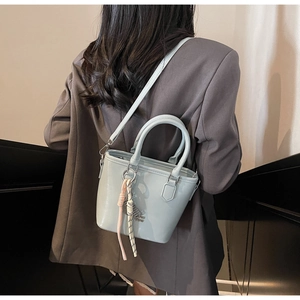 Détail du sac seau en cuir bleu clair avec nœud décoratif et bandoulière porté en travers