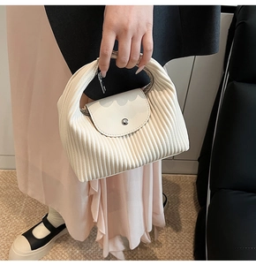 Detail of cream pleated tote bag with smooth flap and decorative metal button closure
