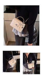 Detail of white quilted box bag with pearl bow, metal heart pendant and chain strap