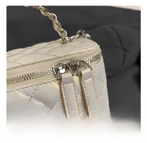 Detail of white quilted leather vanity bag with silver twist lock and dual zippers