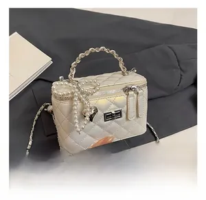 Detail of pearl white quilted mini box bag with pearl bow and heart charm on silver chain