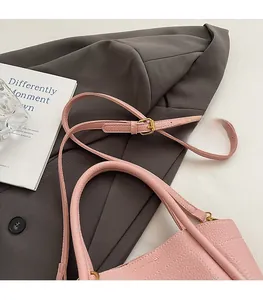 Close-up of pink lychee leather bucket bag with gold hardware and comfortable strap