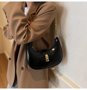 Detail of black crescent moon bag with glossy vintage leather and chunky gold chain strap
