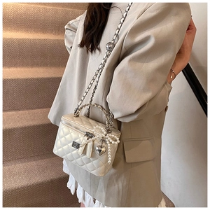 Detail of cream quilted handbag with woven metal handle and pearl chain strap