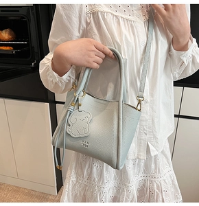 Detailed view of blue litchi grain leather bucket bag with a cute dog-shaped charm