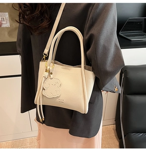Detail of cream leather tote bag with Pan Tor embossed logo and cute dog charm accent